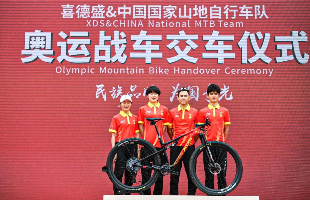中国国家山地自行车队运动员与奥运战车合影